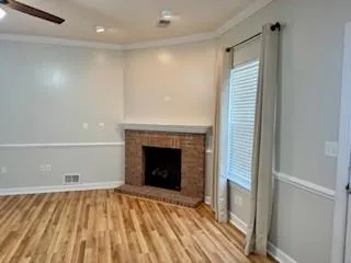 a view of an empty room with wooden floor fireplace and a window