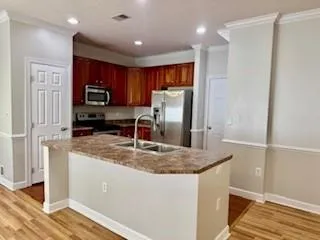 a kitchen with kitchen island granite countertop a refrigerator a stove and a sink with wooden floor