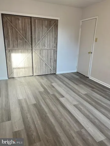 a view of an empty room with wooden floor and door