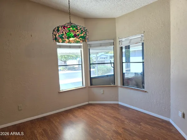 a view of an empty room with chandelier fan and wooden floor