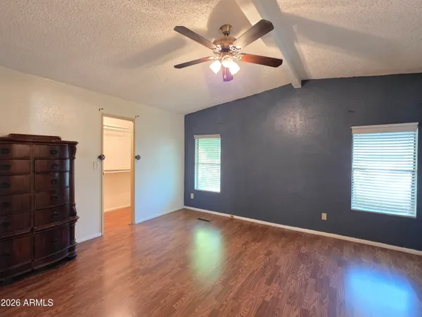 an empty room with wooden floor chandelier fan and windows