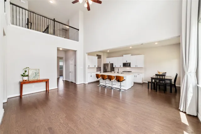 a living room with furniture and a dining table with wooden floor