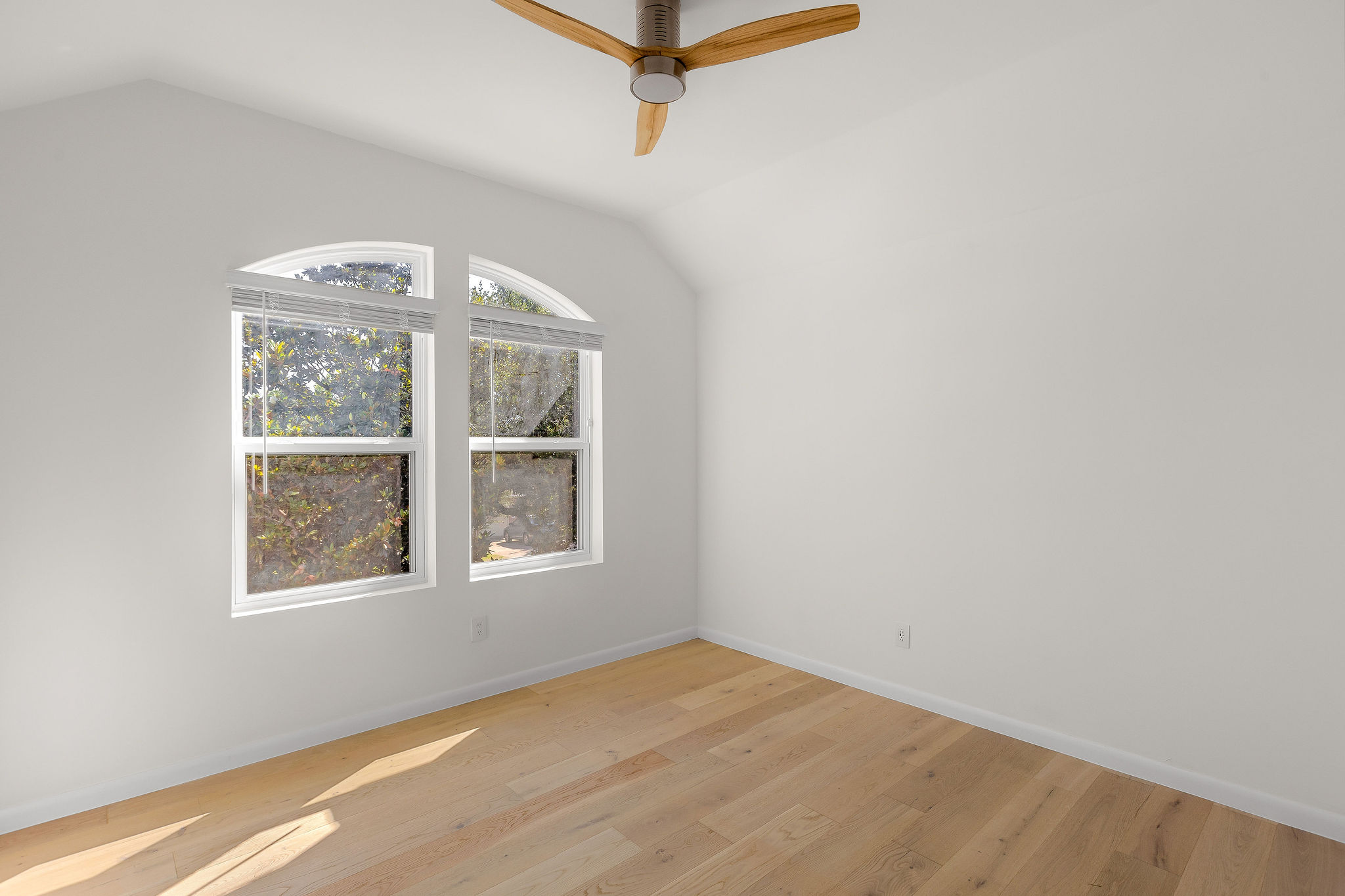 6500 Clay Allison Pass Austin, TX 78749 - Photo 28 of 39 Vaulted ceiling with a wood-blade ceiling fan, two arched-top windows with blinds, and wood-finish flooring