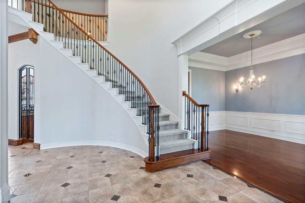 1000 Saddlebrook Drive Lucas, TX 75002 - Photo 7 of 39 Stairway featuring a chandelier, tile patterned floors, a decorative wall, a wainscoted wall, and a high ceiling
