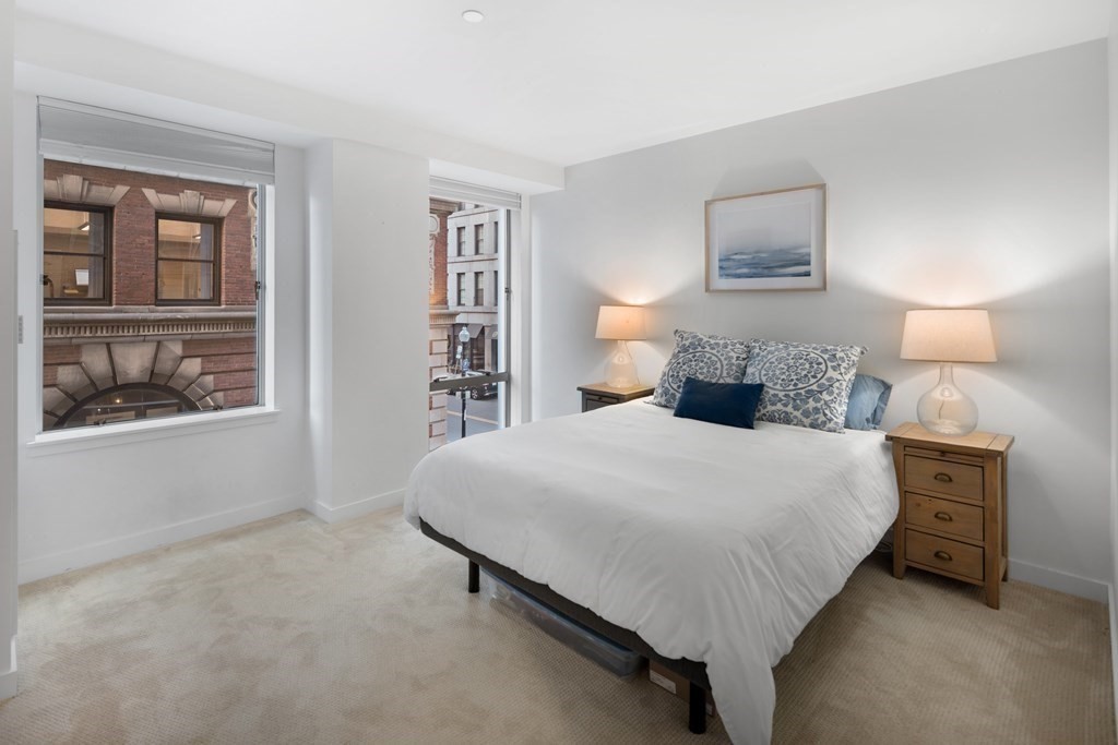 80 Broad Street, Unit 203 Boston, MA 02110 - Photo 5 of 21 a bedroom with a bed and a night stand