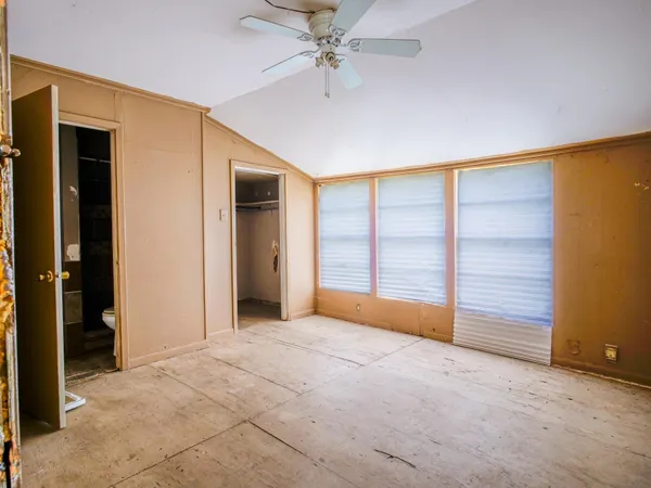 an empty room with wooden floor fan and windows