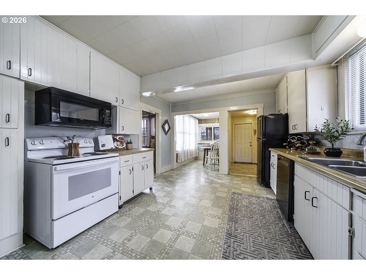 408 Oak Grove Road Medford, OR 97501 - Photo 14 of 46 a kitchen with stainless steel appliances kitchen island granite countertop a refrigerator oven a sink dishwasher and white cabinets with wooden floor