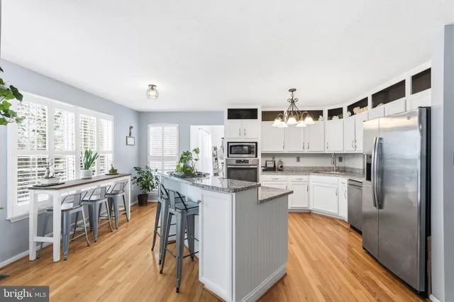 a kitchen with kitchen island a counter top space a sink stainless steel appliances and cabinets