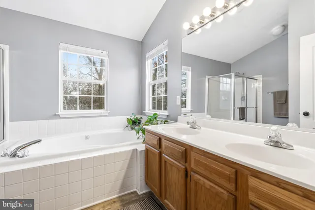 a bathroom with a granite countertop tub sink and mirror