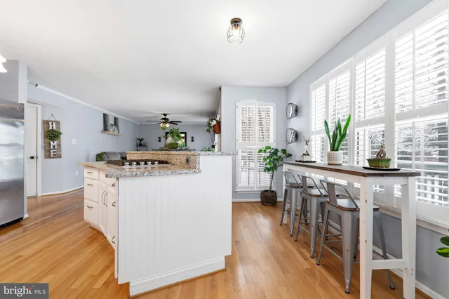 a room with kitchen island a white counter top space a sink and a large window