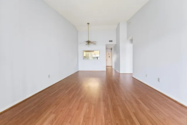 a view of a big room with wooden floor and windows
