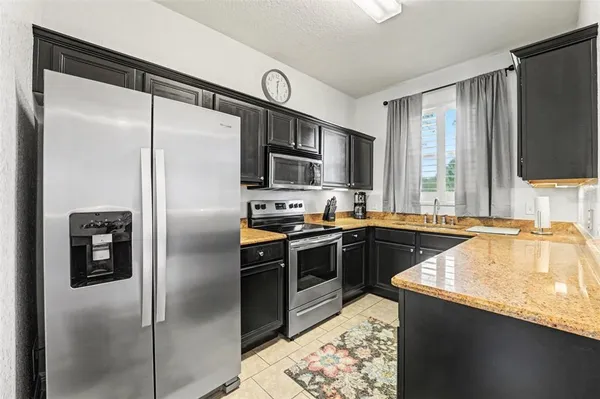 a kitchen with granite countertop a refrigerator a sink a stove and cabinets