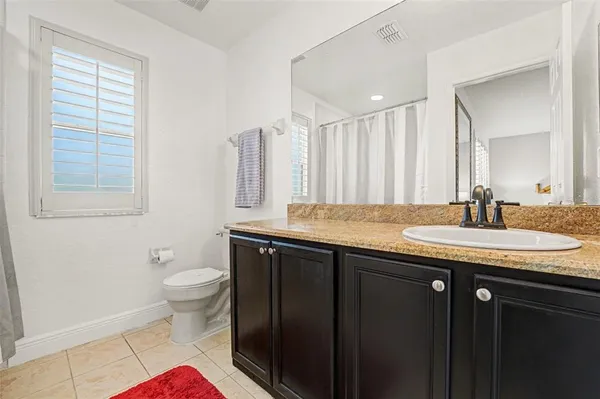 a bathroom with a granite countertop sink a toilet and a mirror