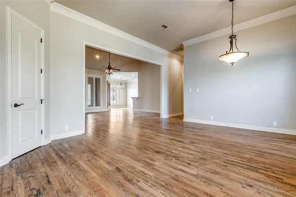 a view of a hallway with wooden floor and chandelier