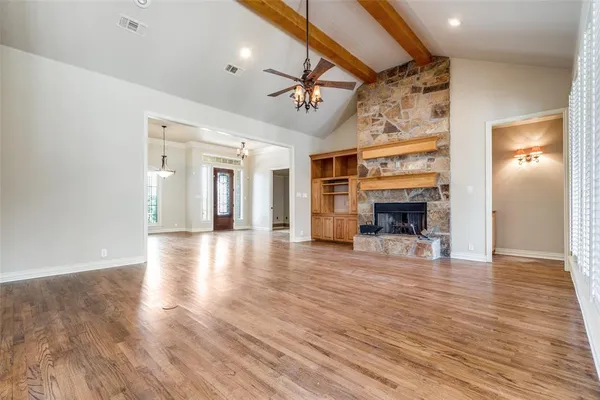 an empty room with wooden floor fireplace and windows