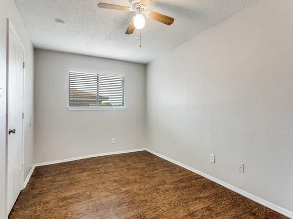 an empty room with a chandelier fan and windows