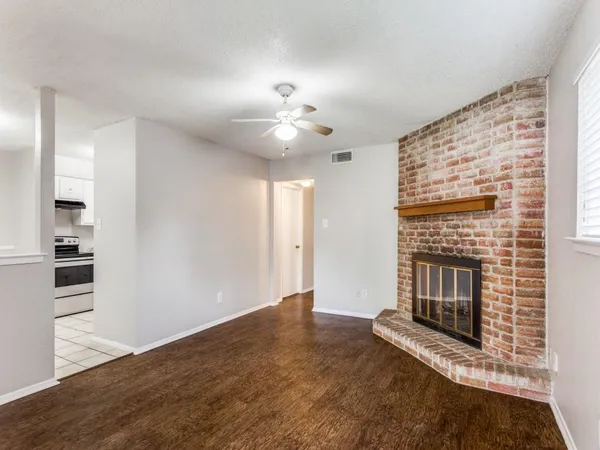 a view of an empty room with chandelier fan and fire place