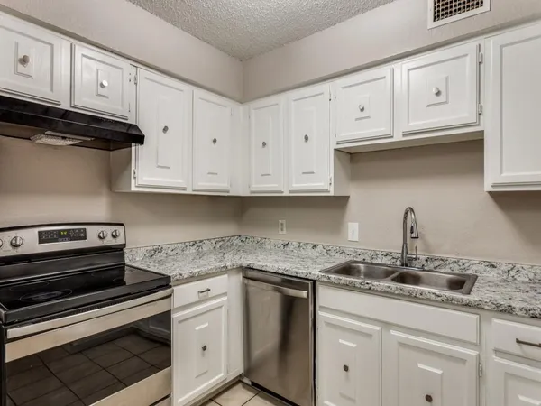 a kitchen with granite countertop white cabinets and a stove