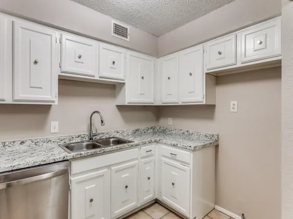 a kitchen with stainless steel appliances granite countertop white cabinets sink and dishwasher