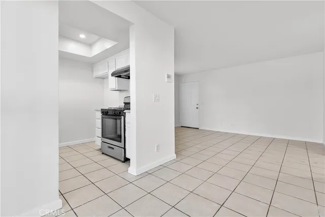 an empty room with kitchen view and wooden floor