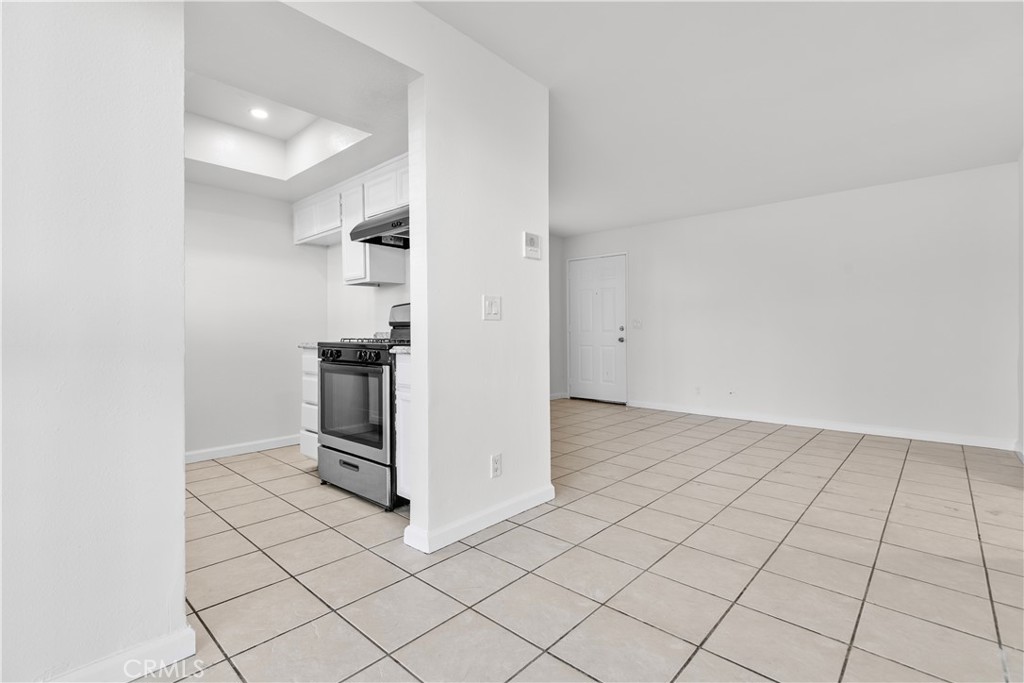 5915 Woodman Avenue, Unit 103 Van Nuys, CA 91401 - Photo 3 of 9 an empty room with kitchen view and wooden floor
