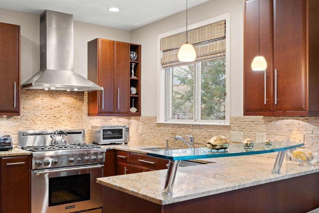 214 Allandale Road, Unit D Boston, MA 02467 - Photo 15 of 40 a kitchen with stainless steel appliances granite countertop a stove a sink and a microwave