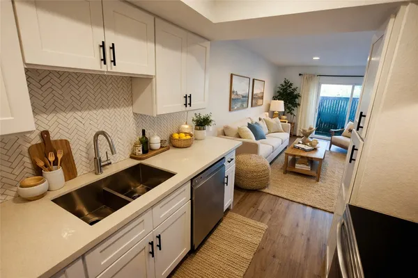 a large white kitchen with a stove a sink dishwasher and white cabinets with wooden floor