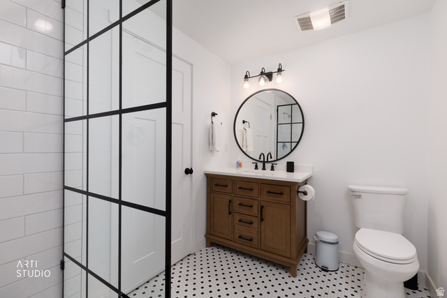 1654 South 730 West Provo, UT 84601 - Photo 25 of 33 Bathroom featuring a dark wood vanity with a white countertop, round mirror, and black fixtures