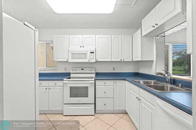 a kitchen with white cabinets appliances a sink and a window