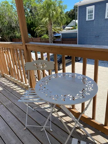 a view of a patio with table and chairs with wooden floor and fence