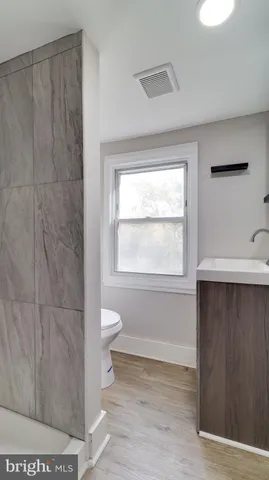 a bathroom with a toilet a sink a window and shower