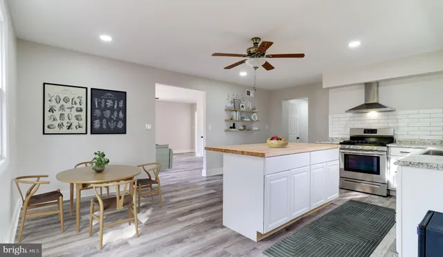 a kitchen with stainless steel appliances kitchen island granite countertop a table chairs and a refrigerator
