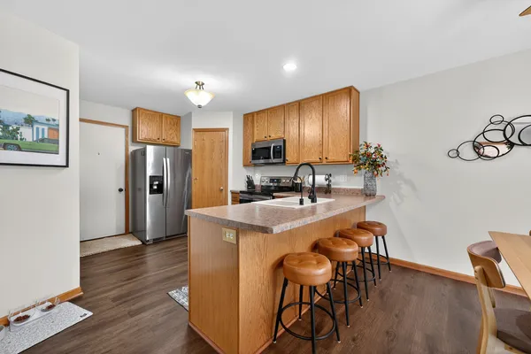 a kitchen with stainless steel appliances granite countertop a refrigerator a stove a sink a dining table and chairs with wooden floor