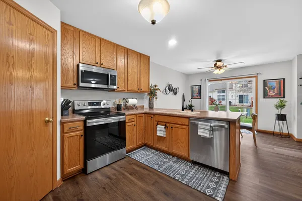 a kitchen with stainless steel appliances granite countertop a stove top oven a sink dishwasher a microwave oven and a refrigerator with wooden floor