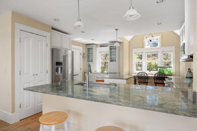 a kitchen with stainless steel appliances granite countertop a stove a sink dishwasher a microwave oven and a dining table with wooden floor