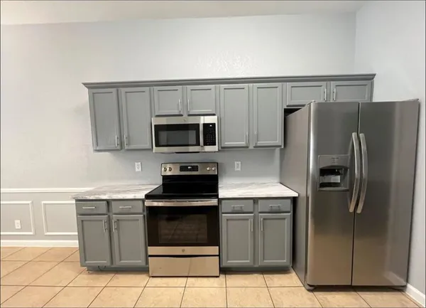 a kitchen with granite countertop a refrigerator and a stove top oven