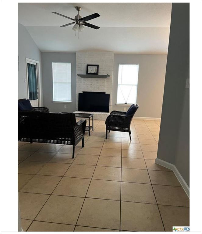7108 Bluegrass Court Temple, TX 76502 - Photo 7 of 19 a living room with a black white checkered floor with a fireplace and a large window