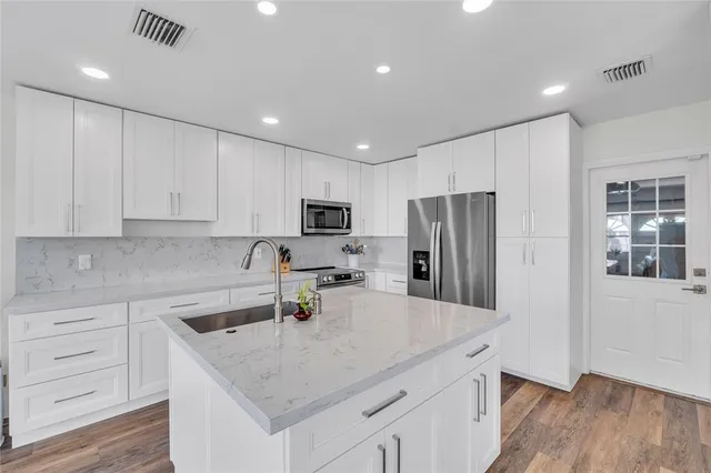 a kitchen that has a lot of cabinets a sink and appliances in it