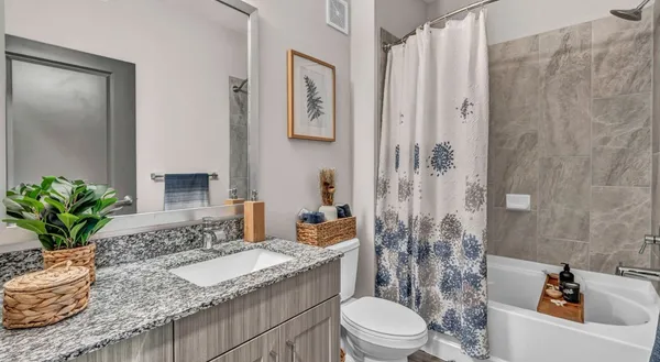 a bathroom with a granite countertop sink a toilet a mirror and shower