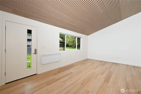 an empty room with wooden floor and windows