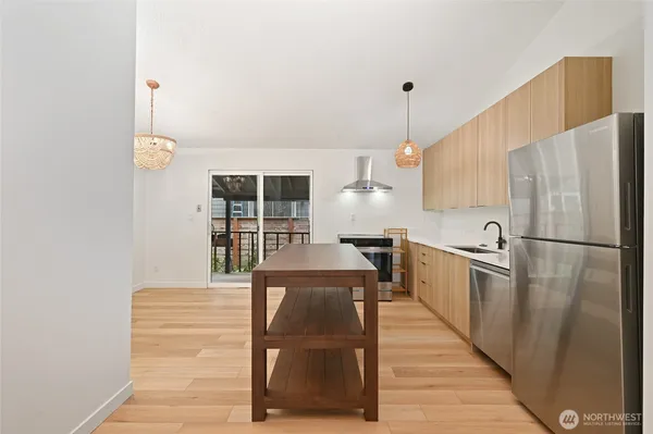 a kitchen with stainless steel appliances granite countertop a refrigerator a oven and white cabinets with wooden floors