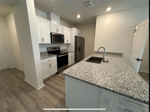 a kitchen with stainless steel appliances granite countertop a sink refrigerator and microwave