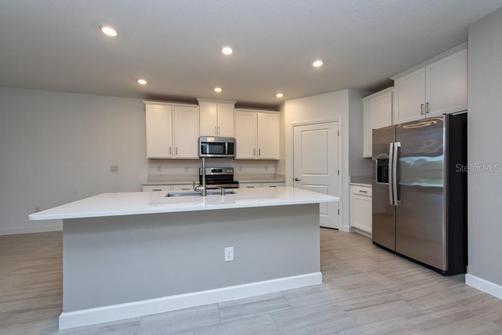 10976 Gable Dig Loop San Antonio, FL 33576 - Photo 10 of 37 a kitchen with stainless steel appliances a sink a stove a refrigerator and cabinets