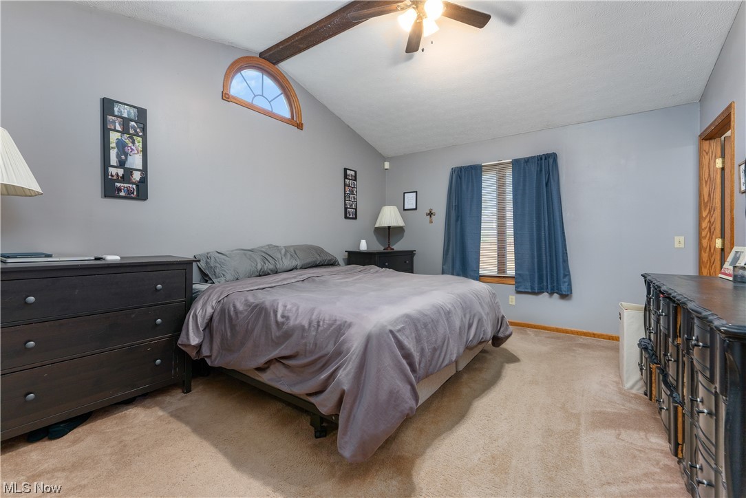 5226 Johnnycake Ridge Northeast Canton, OH 44705 - Photo 19 of 32 Carpeted bedroom featuring multiple windows, ceiling fan, and lofted ceiling with beams