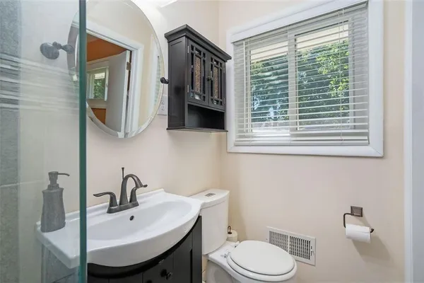 a bathroom with a sink a mirror a toilet and a window