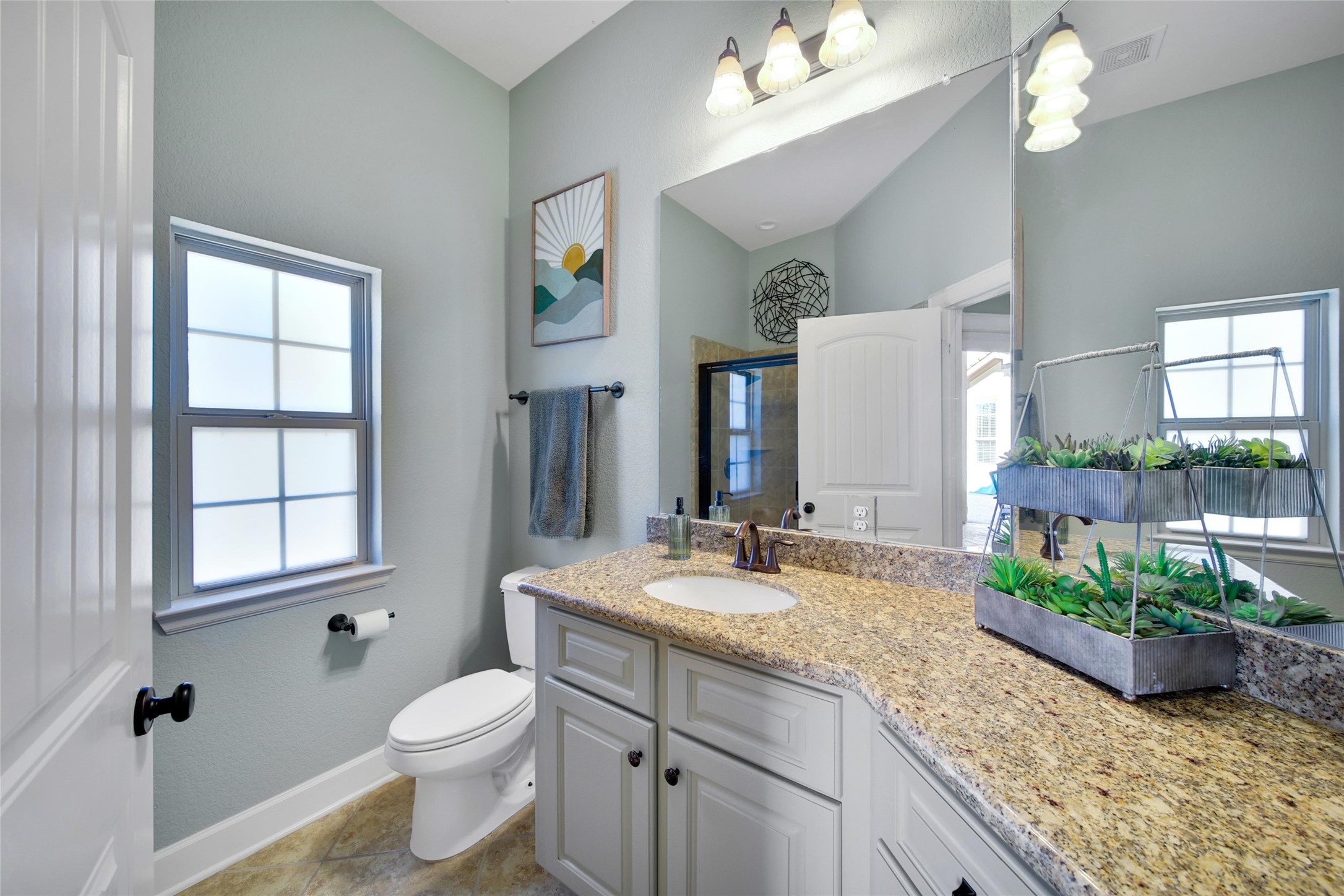 26122 Crown Ranch Boulevard Montgomery, TX 77316 - Photo 18 of 31 a bathroom with a granite countertop sink a toilet a mirror and window
