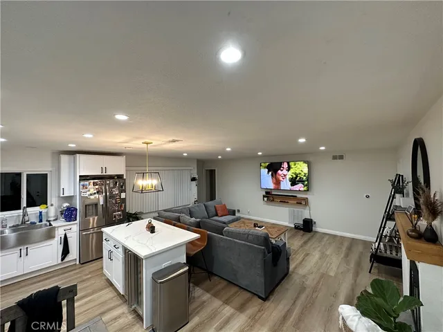 a living room with furniture a flat screen tv and a refrigerator