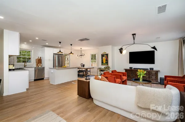 a living room with furniture kitchen view and a flat screen tv