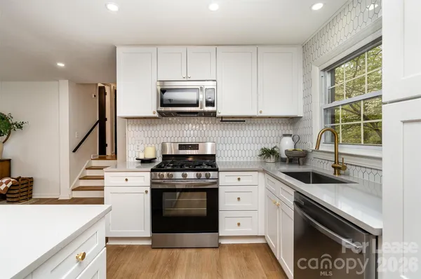 a kitchen with stainless steel appliances a sink a stove and cabinets