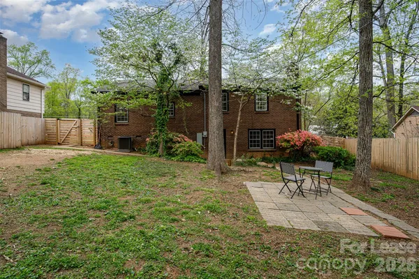 a view of a backyard with table and chairs potted plants and a large tree